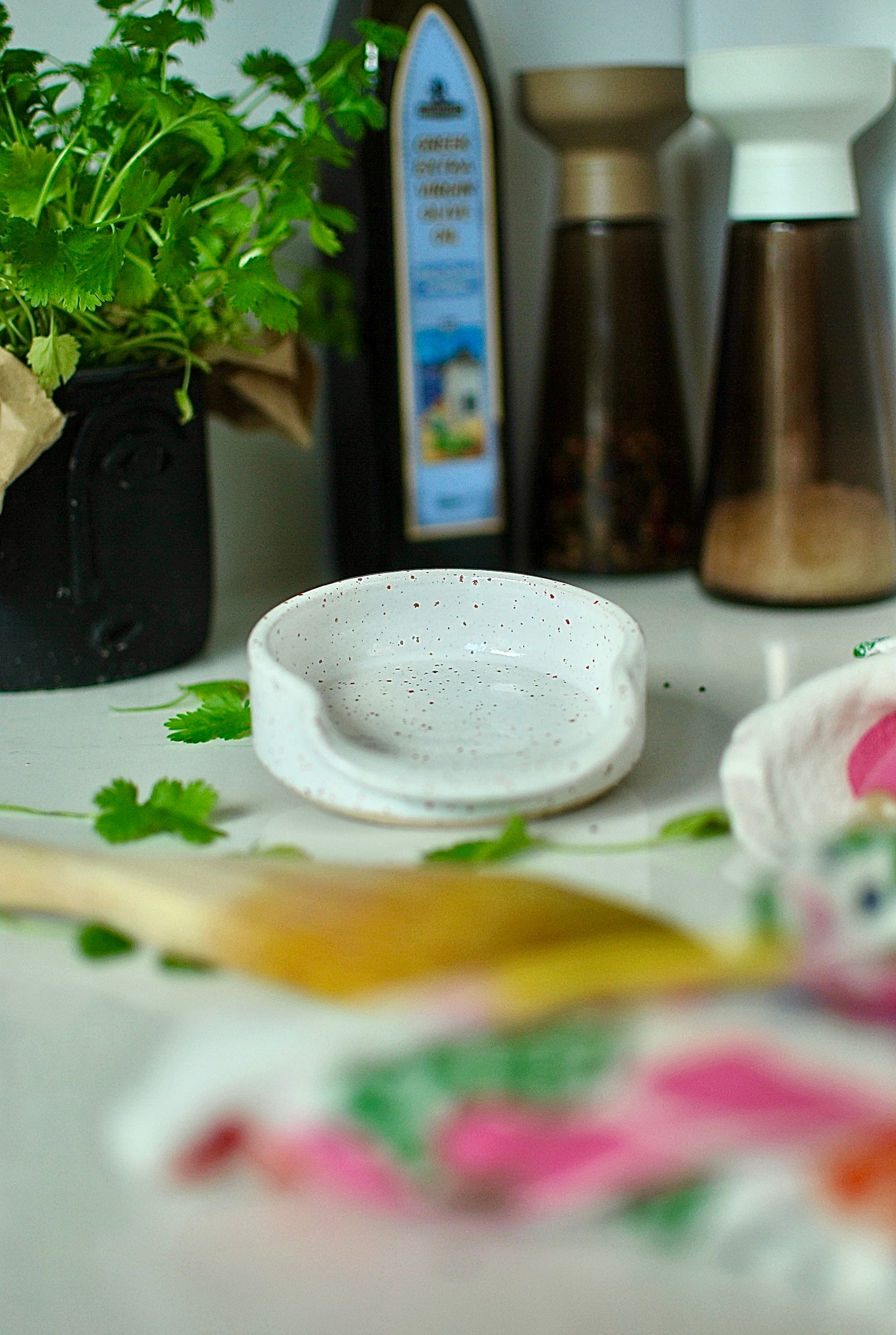 A white speckled stoneware Chamonix spoon rest with a scalloped edge.