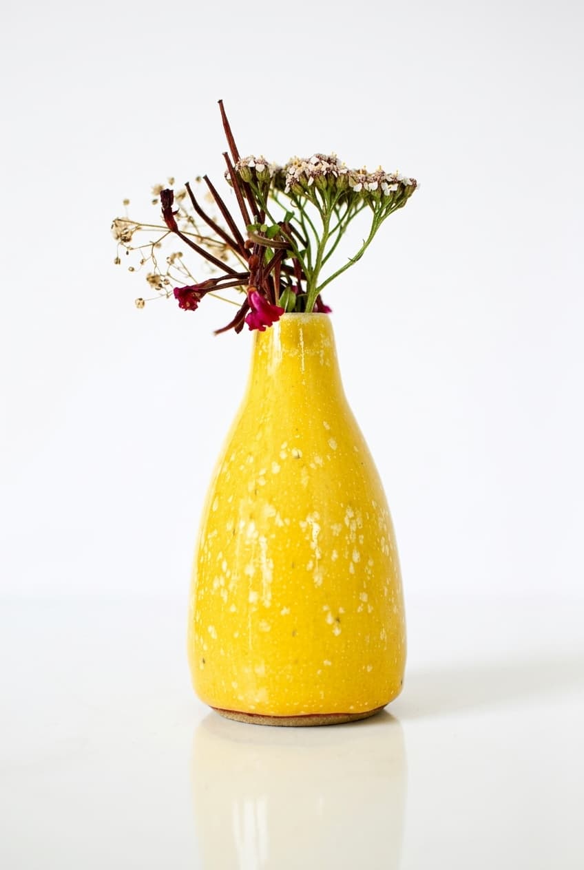 Handmade yellow ceramic vase with a bright vivid yellow glaze created by layering white and yellow glazes, displayed with dried wildflowers. Handmade and wheel-thrown in Dublin, Ireland by Studio Lippi Ceramics