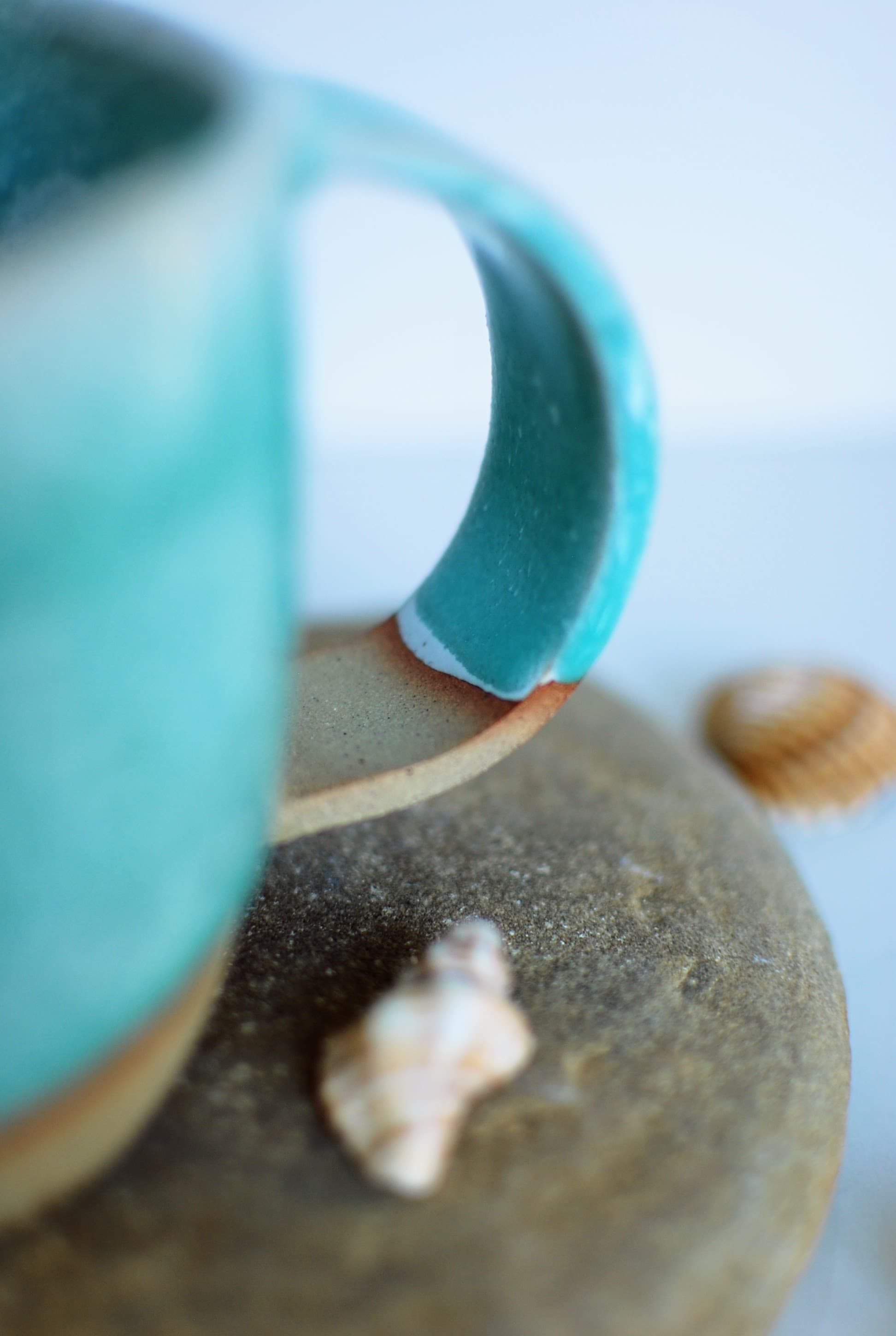 Close-up of a handmade ceramic mug handle with turquoise glaze and a natural stoneware accent, showcasing the craftsmanship of Studio Lippi Ceramics in Dublin.